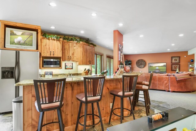 7548 Fallen Oak Dr, Verona, WI 53593 - kitchen featuring a kitchen breakfast bar, appliances with stainless steel finishes, light stone counters, and recessed lighting