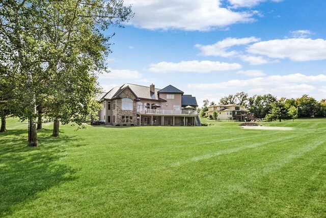 7548 Fallen Oak Dr, Verona, WI 53593 - rear view of house with stone siding, a chimney, a deck, metal roof, and a lawn