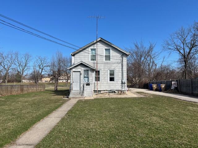 view of front facade with a front yard, fence, and entry steps