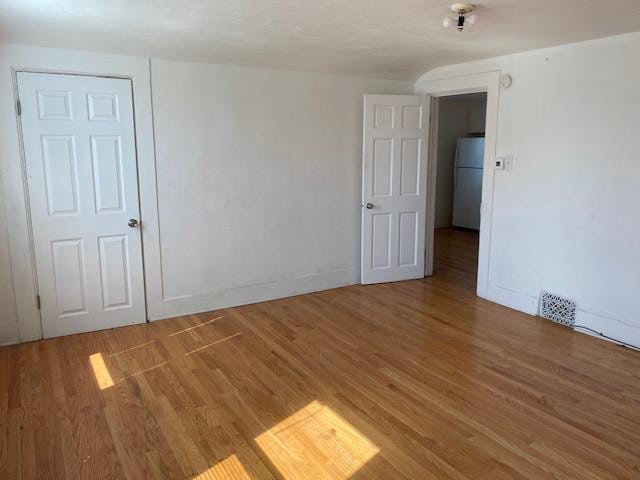 spare room featuring visible vents, baseboards, and light wood-type flooring