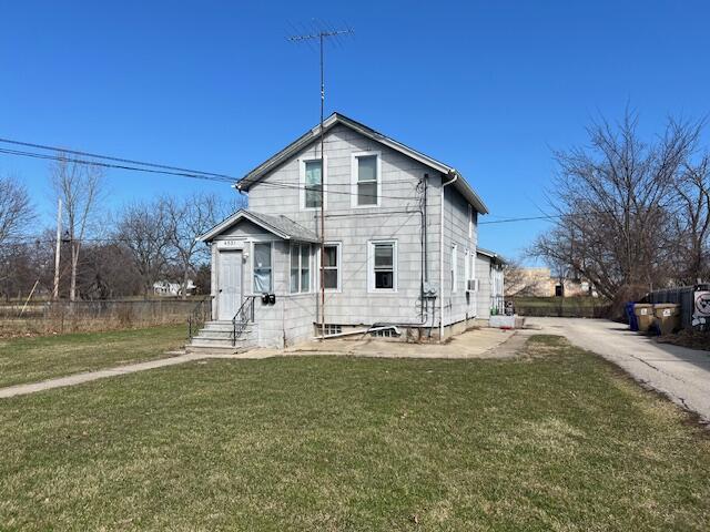 view of front of home with a front yard, fence, and entry steps