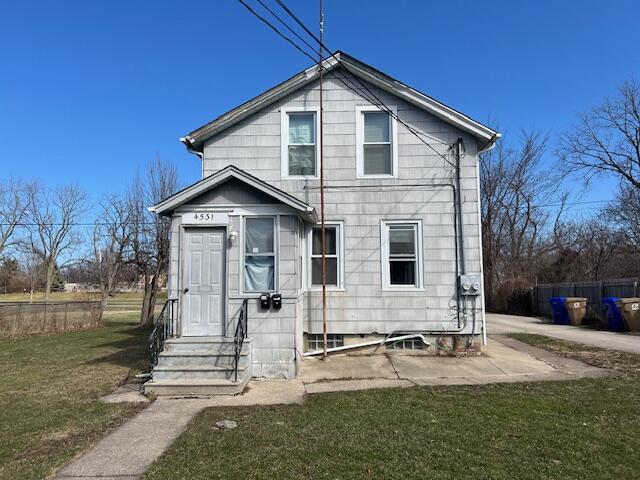 rear view of house featuring entry steps, fence, and a yard