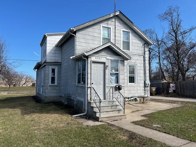 view of front of home featuring entry steps, fence, and a front yard