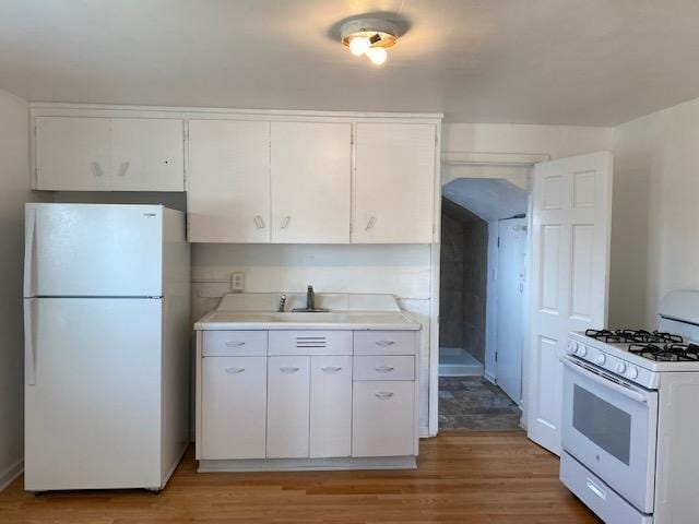 kitchen featuring light countertops, a sink, white cabinetry, light wood-type flooring, and white appliances