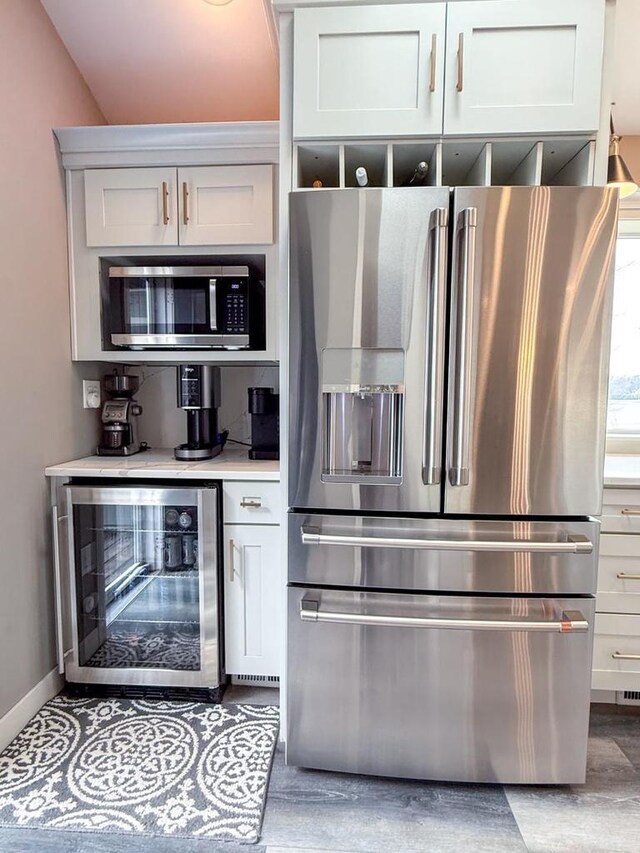 kitchen with light countertops, white cabinets, baseboards, stainless steel appliances, and beverage cooler