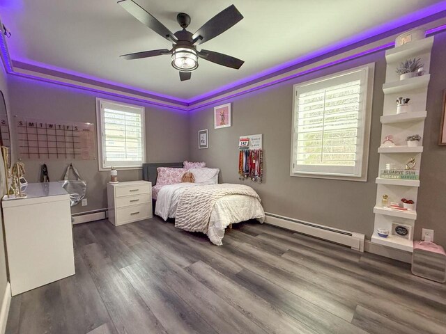 bedroom featuring baseboard heating, wood finished floors, and a ceiling fan