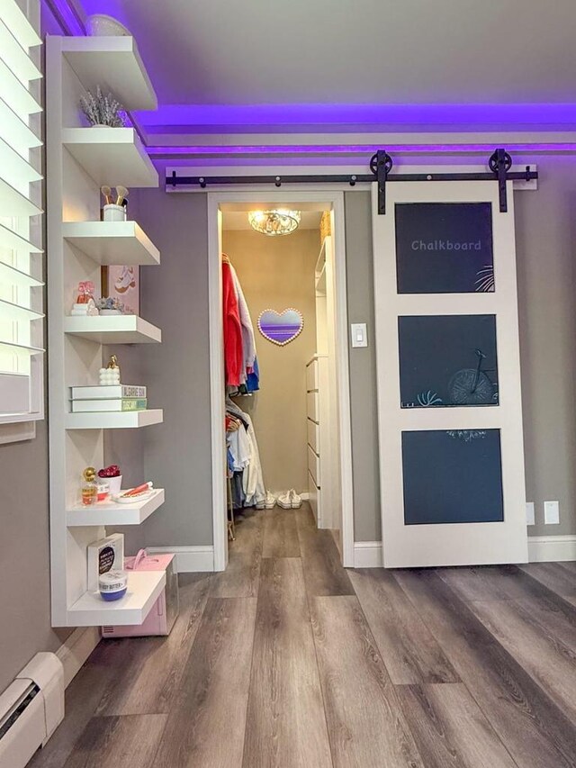 hall featuring baseboards, a barn door, wood finished floors, and a baseboard radiator