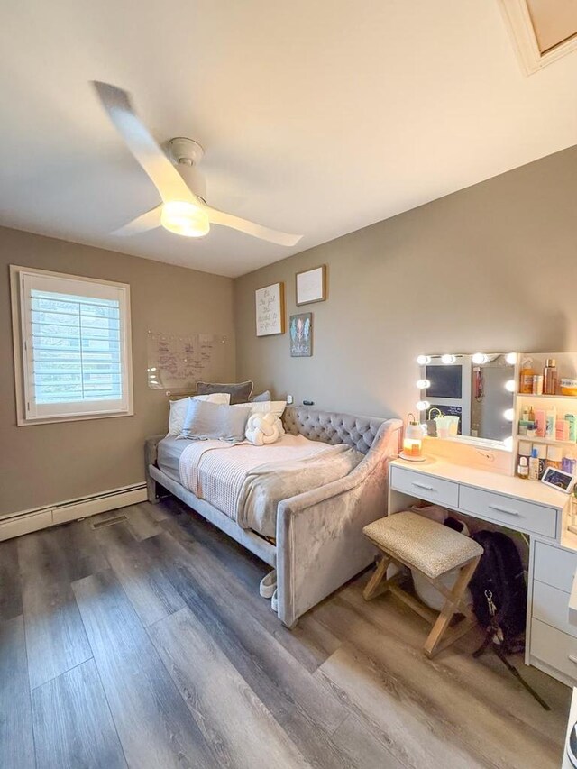 bedroom with baseboards, baseboard heating, wood finished floors, and a ceiling fan