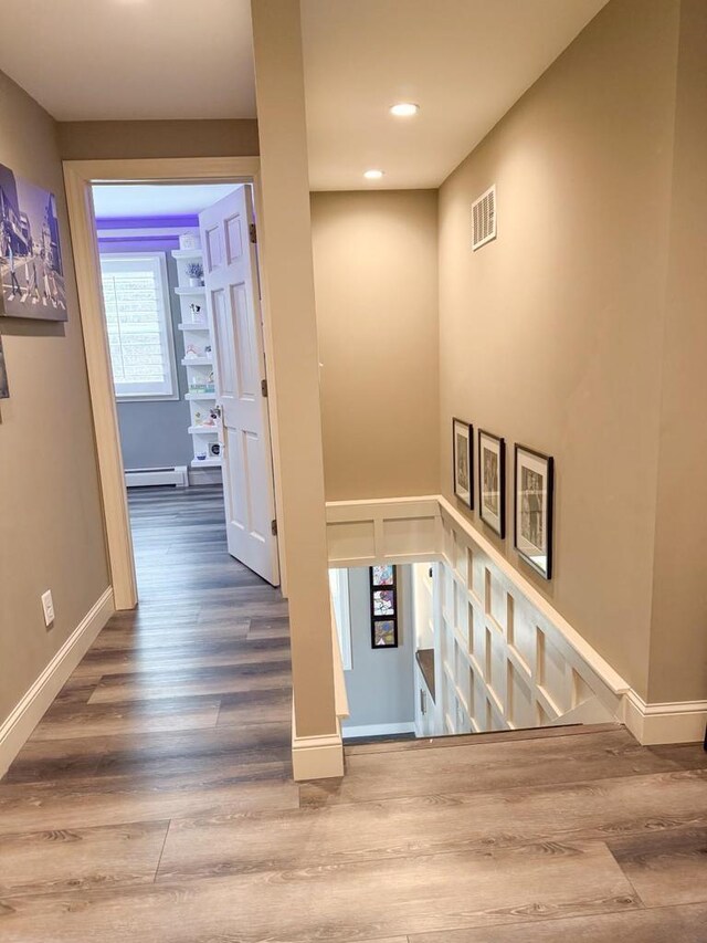stairway with recessed lighting, baseboards, visible vents, a baseboard radiator, and wood finished floors