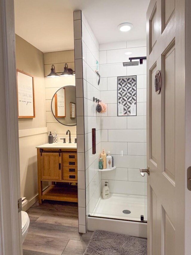 bathroom featuring a stall shower, toilet, wood finished floors, and vanity