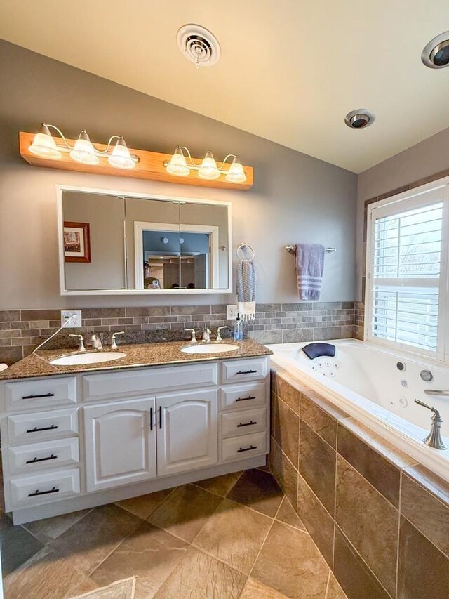 bathroom featuring a sink, a jetted tub, lofted ceiling, and visible vents
