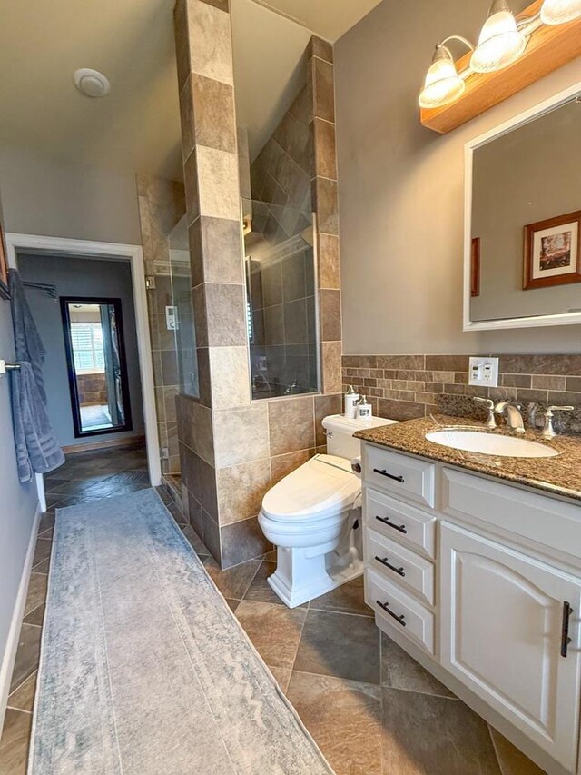 full bath with tile walls, toilet, tile patterned floors, vanity, and a stall shower