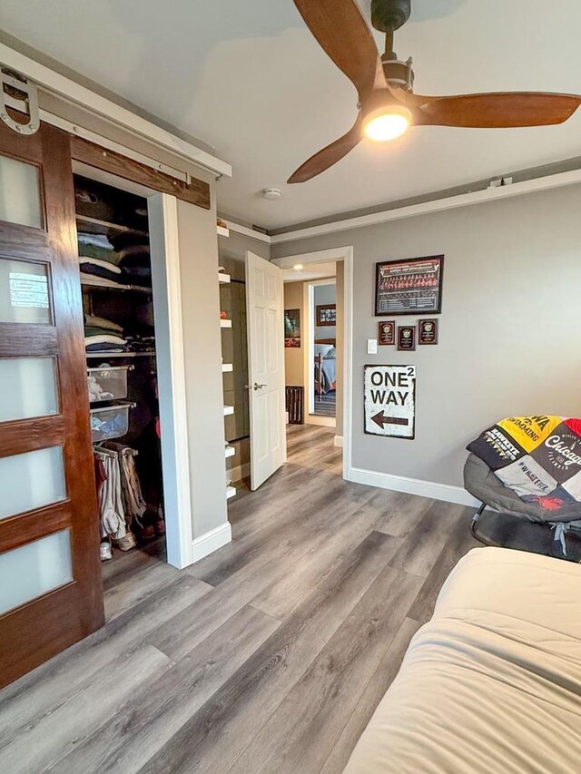bedroom featuring a ceiling fan, baseboards, a closet, and wood finished floors