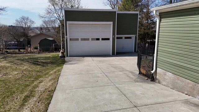 garage with fence and concrete driveway
