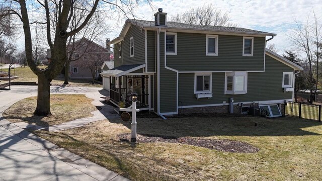 view of home's exterior featuring a chimney, fence, and a yard