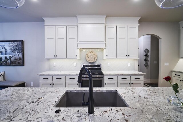 2721 Woodfield Ct, Howard, WI 54313 - kitchen featuring backsplash, a sink, light stone countertops, gas stove, and arched walkways