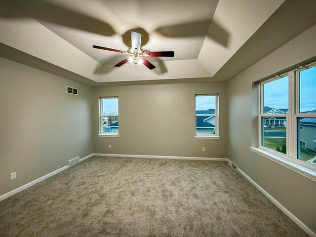 2208 W Milwaukee St, Stoughton, WI 53589 - spare room with a tray ceiling, carpet, baseboards, visible vents, and a ceiling fan