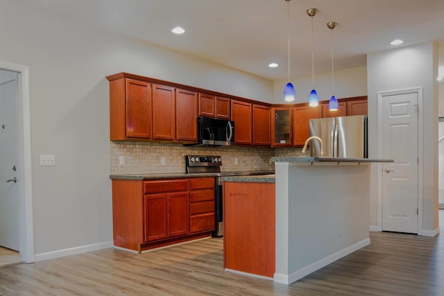 2208 W Milwaukee St, Stoughton, WI 53589 - kitchen with stainless steel appliances, dark countertops, tasteful backsplash, decorative light fixtures, and light wood-style floors