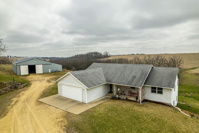 5995 Section Line Rd, Dodgeville, WI 53533 - exterior space with dirt driveway, an attached garage, a front lawn, an outbuilding, and a shingled roof