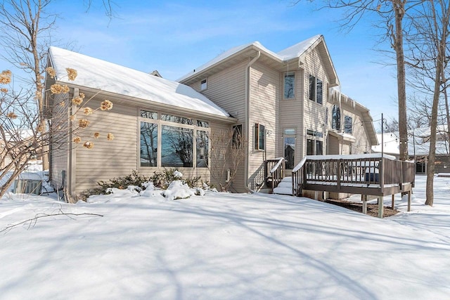 snow covered house featuring a wooden deck