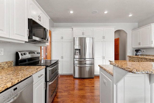 kitchen featuring arched walkways, appliances with stainless steel finishes, wood finished floors, and white cabinetry