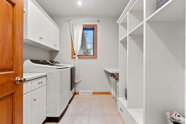 laundry room featuring light tile patterned floors, independent washer and dryer, visible vents, baseboards, and cabinet space