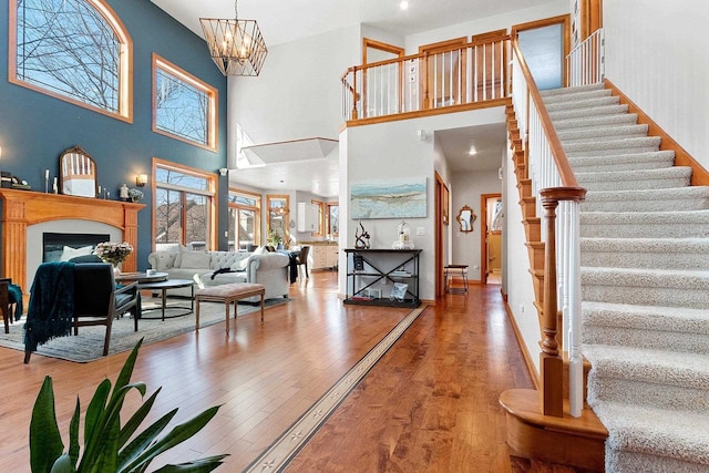 interior space with a fireplace, a towering ceiling, wood finished floors, and stairs