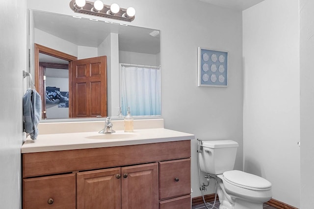 full bathroom with toilet, vanity, and baseboards