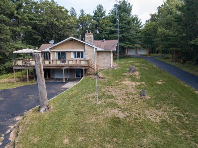 1930 Czech Ave, Arkdale, WI 54613 - view of front facade with a wooden deck, aphalt driveway, a front yard, a garage, and a chimney