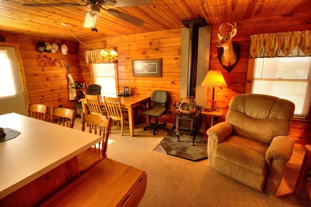 N16180 Deerfield Dr, Nekoosa, WI 54457 - carpeted living area featuring wood ceiling, wood walls, ceiling fan, and a wood stove