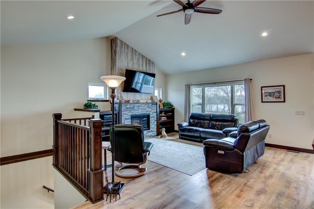living area with a ceiling fan, plenty of natural light, a fireplace, and wood finished floors