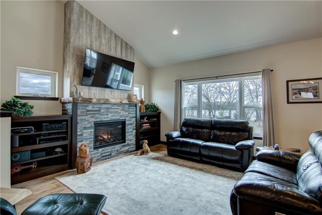 living area with wood finished floors, vaulted ceiling, recessed lighting, and a stone fireplace