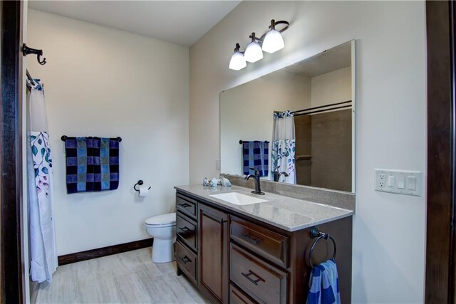 bathroom with baseboards, toilet, a shower with shower curtain, and vanity