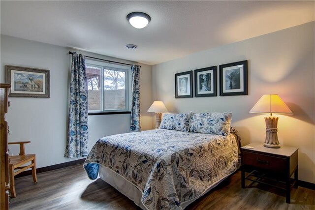 bedroom featuring baseboards, visible vents, and wood finished floors