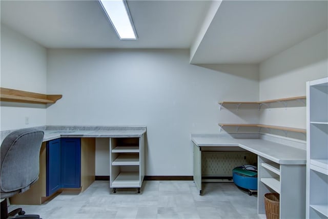 unfurnished office with baseboards, light floors, and built in study area