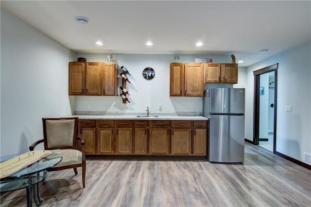 kitchen with light countertops, light wood-style flooring, brown cabinets, and freestanding refrigerator