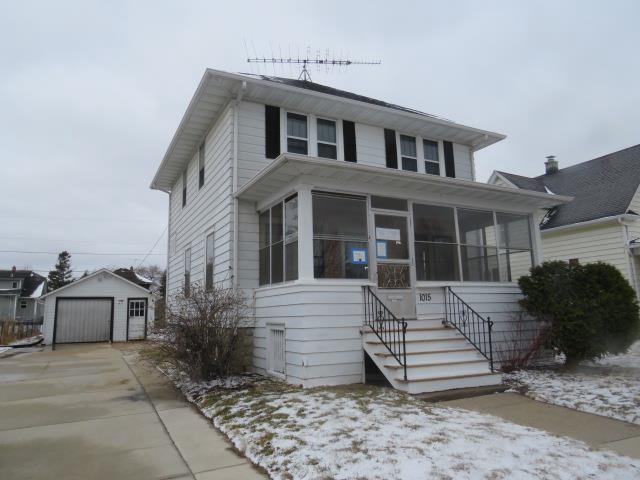 1015 Wisconsin Ave, North Fond Du Lac, WI 54937 - view of front of house featuring an outdoor structure, a sunroom, driveway, and a garage