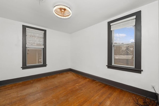 spare room featuring baseboards and dark wood finished floors