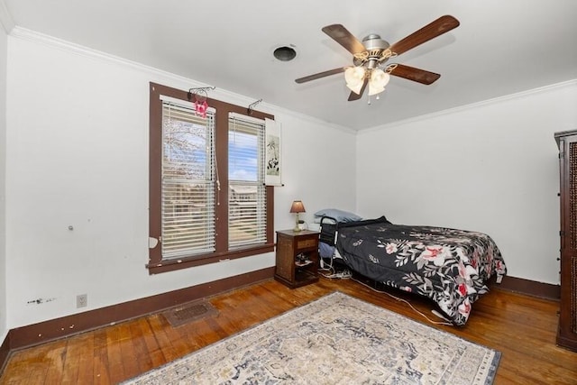 bedroom featuring baseboards, ornamental molding, wood finished floors, and a ceiling fan