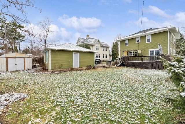 rear view of property with an outbuilding, a storage unit, and a deck