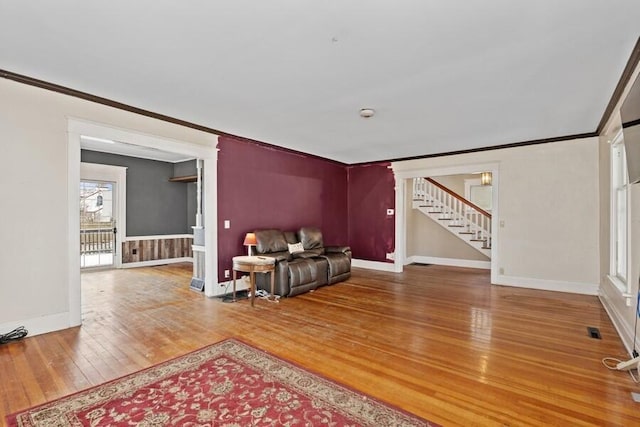 living room featuring baseboards, stairs, crown molding, and wood-type flooring
