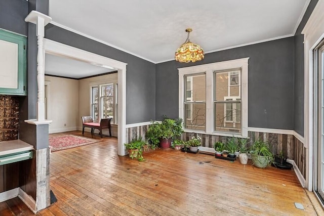 dining room featuring crown molding, ornate columns, hardwood / wood-style floors, baseboards, and a notable chandelier