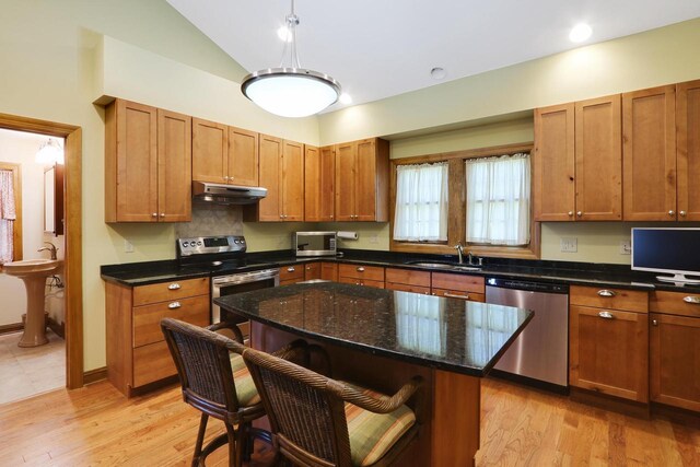 W512 Hafs Rd, Genoa City, WI 53128 - kitchen with vaulted ceiling, a sink, a breakfast bar, appliances with stainless steel finishes, and under cabinet range hood