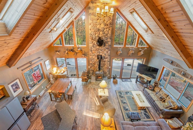 W7113 Bighorn Ct, Wautoma, WI 54982 - unfurnished living room featuring wood finished floors, an inviting chandelier, beam ceiling, a wealth of natural light, and a wood stove
