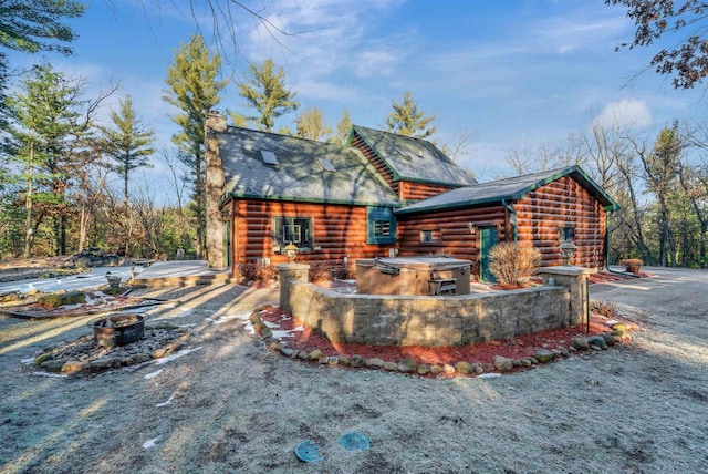 W7113 Bighorn Ct, Wautoma, WI 54982 - view of side of property featuring log siding, a chimney, a fire pit, and roof with shingles
