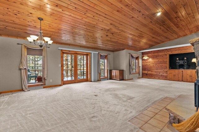 unfurnished living room with carpet floors, an inviting chandelier, and plenty of natural light