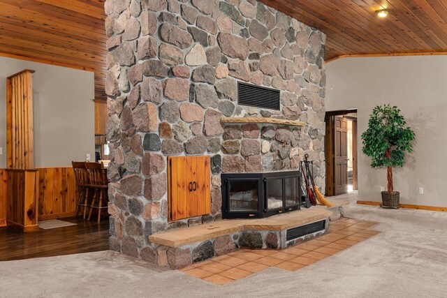 carpeted living room with wood walls, ornamental molding, a stone fireplace, lofted ceiling, and wood ceiling