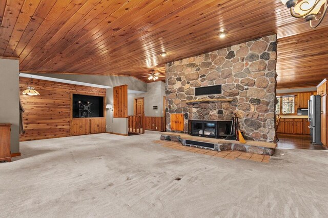 unfurnished living room with visible vents, wooden walls, a ceiling fan, carpet floors, and wooden ceiling