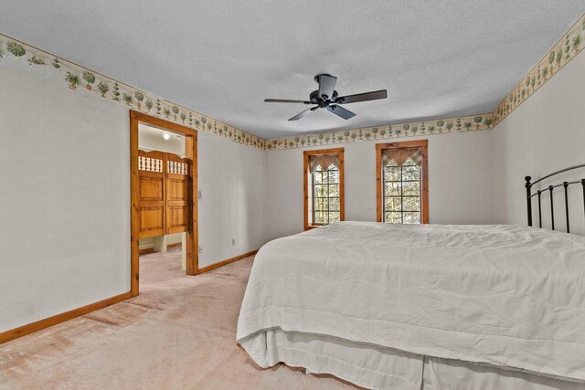 bedroom with ceiling fan, baseboards, light colored carpet, and a textured ceiling