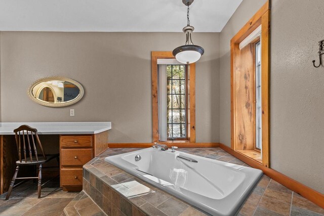 full bathroom featuring vanity, stone tile floors, and a garden tub